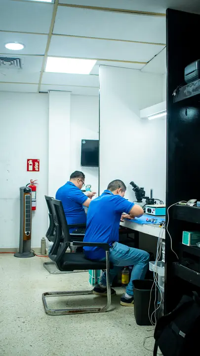 Dos técnicos reparando celulares en sus puestos